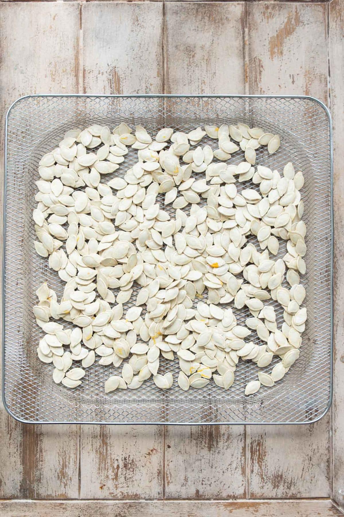 Dry pumpkin seeds in a single layer in an air fryer basket.