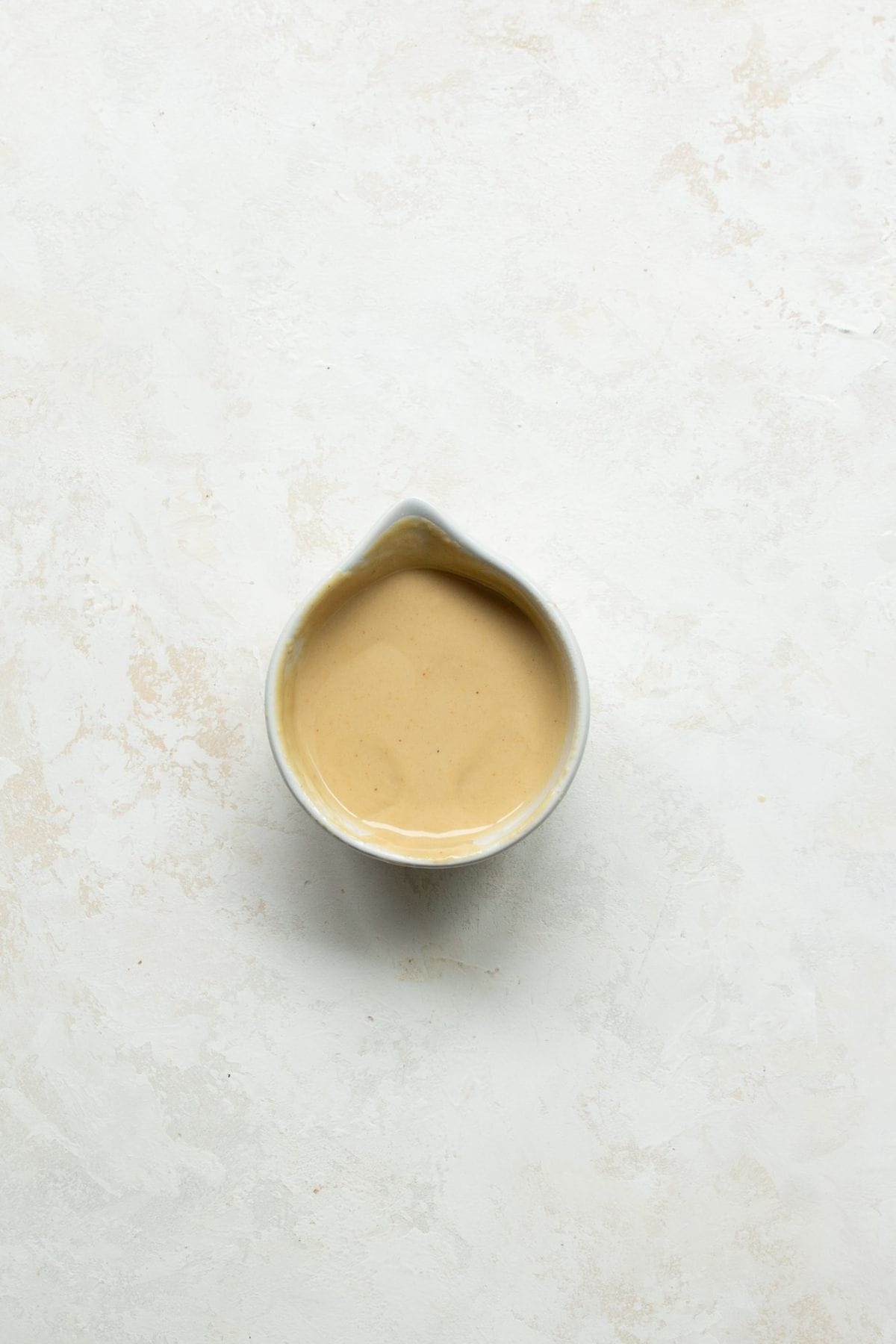 Creamy tahini dressing in a small white bowl.
