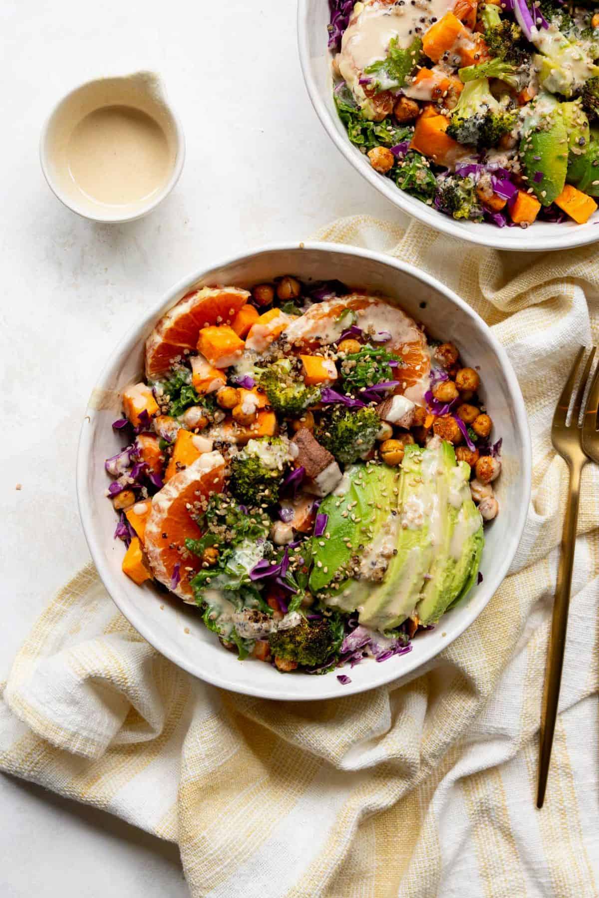 Quinoa sweet potato bowl with creamy tahini dressing, avocado, and orange slices.