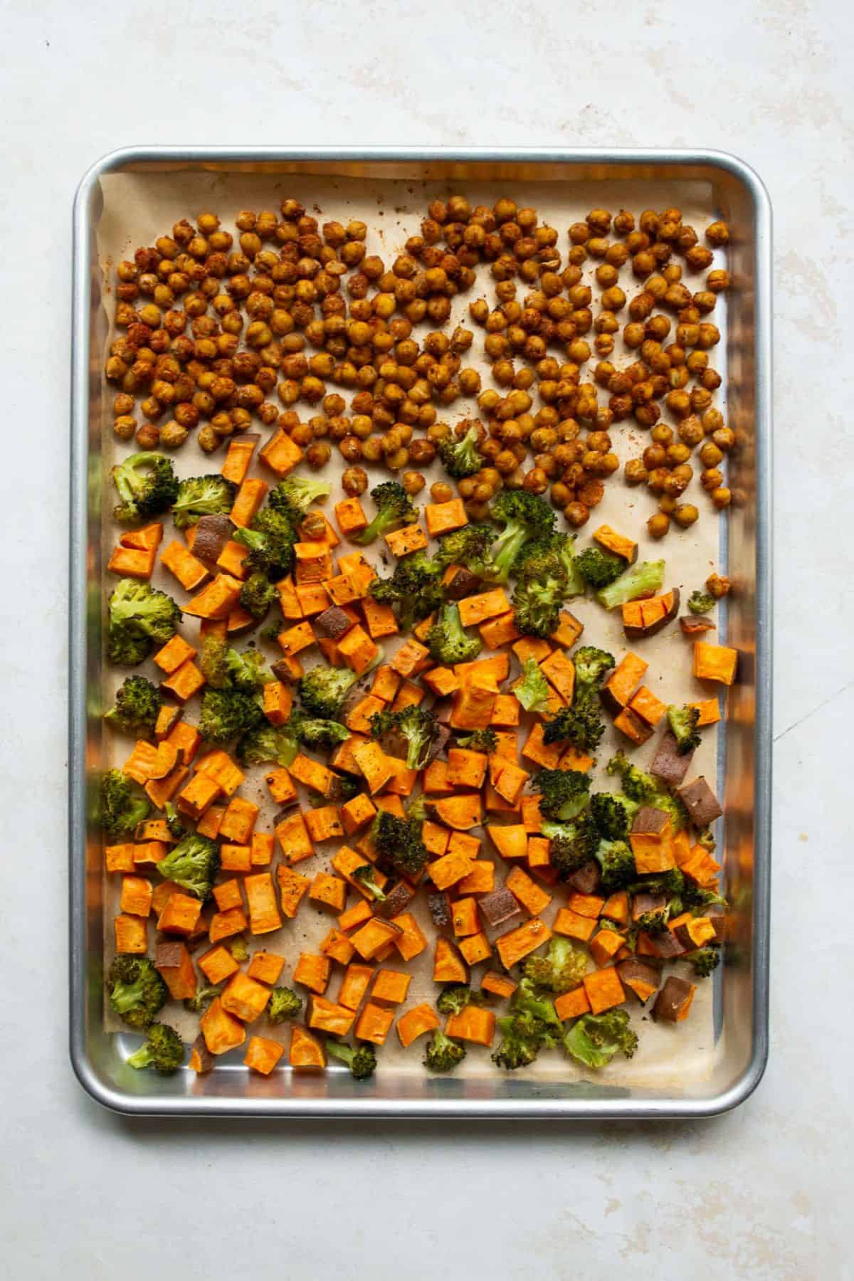 Roasted sweet potatoes, charred broccoli, and crispy chickpeas on a sheet pan.