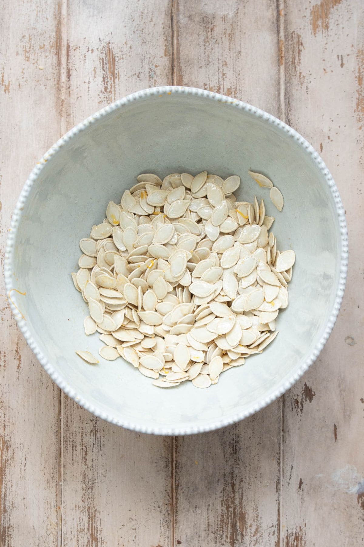 Warm pumpkin seeds tossed with seasoning in a bowl.