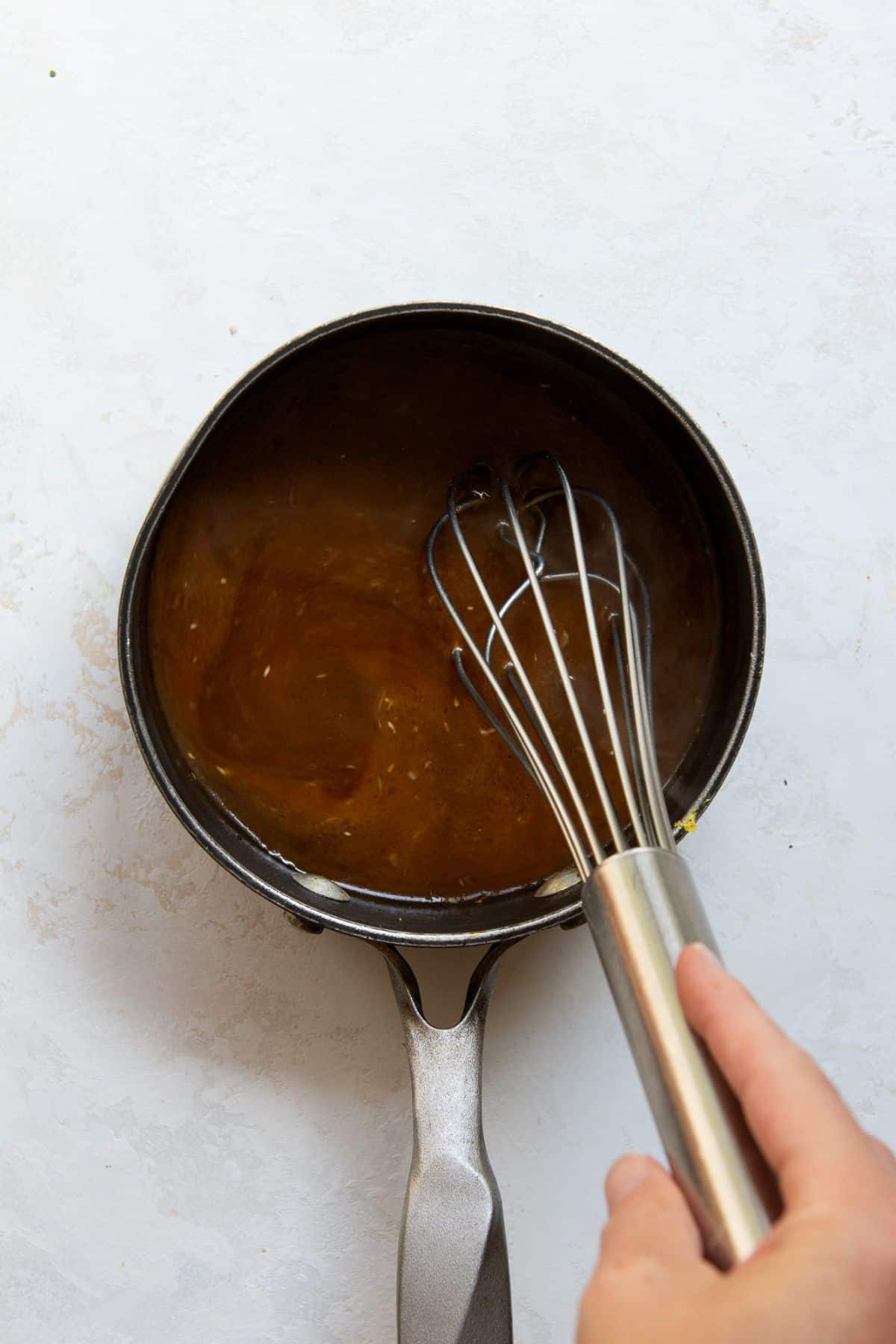 Sticky sesame glaze being whisked in a small saucepan.