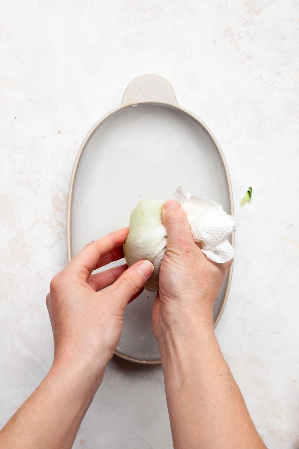 Squeezing water out of grated cucumber in a cheesecloth.