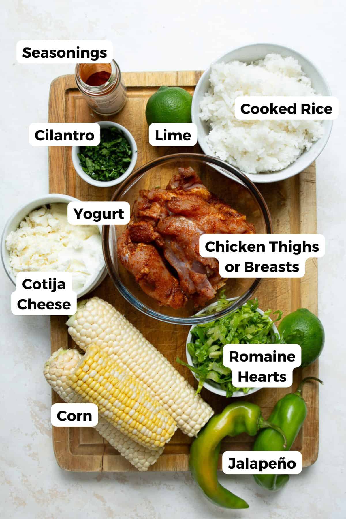 Labeled ingredients for street corn chicken bowls including chicken, limes, seasonings, corn, cotija, romaine lettuce, cilantro, and rice.