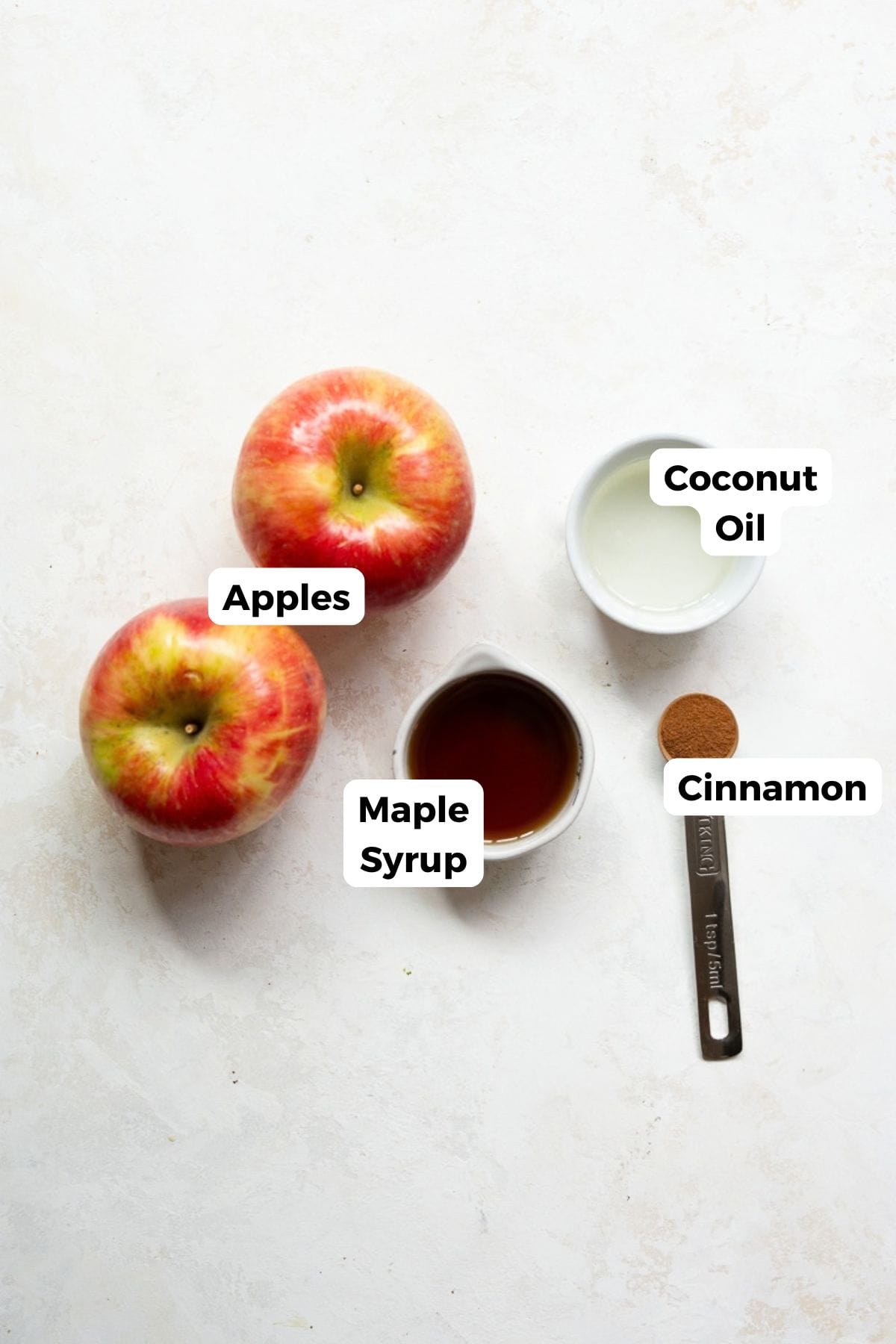Ingredients for air fryer apples: two Honeycrisp apples, maple syrup, coconut oil, and a teaspoon of cinnamon.