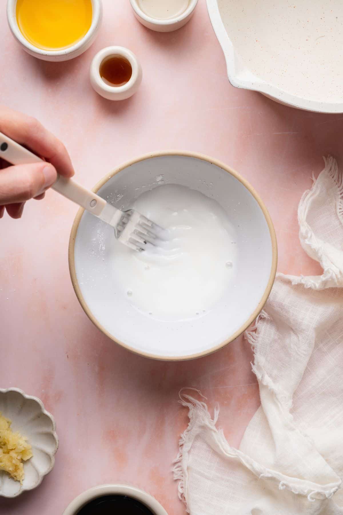 Whisking arrowroot starch and cold water in a small bowl to thicken teriyaki sauce.