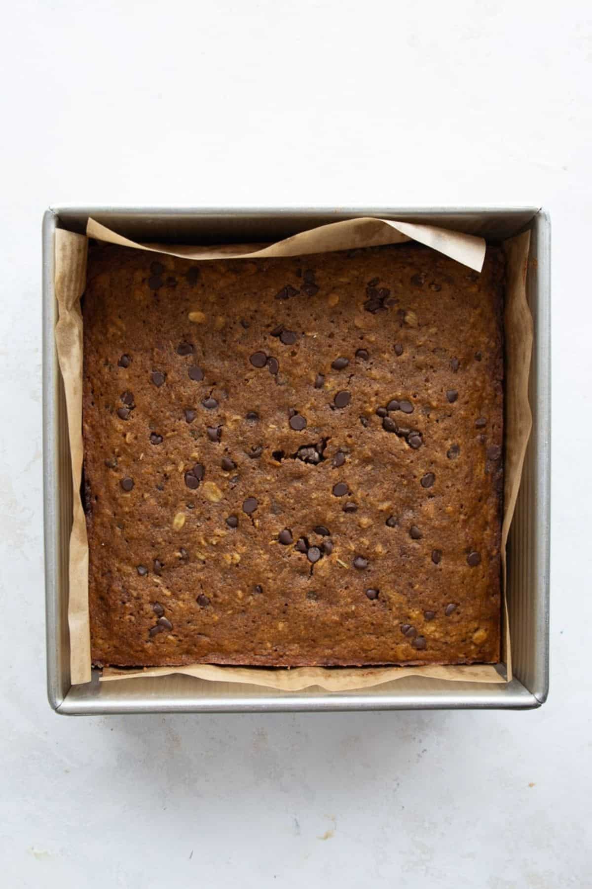 Baked pumpkin oatmeal bars in a parchment-lined 8x8 metal pan.
