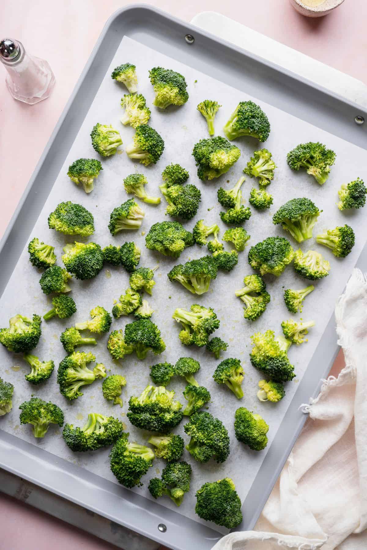 Broccoli florets tossed in olive oil and spread in a single layer on a parchment-lined sheet pan.