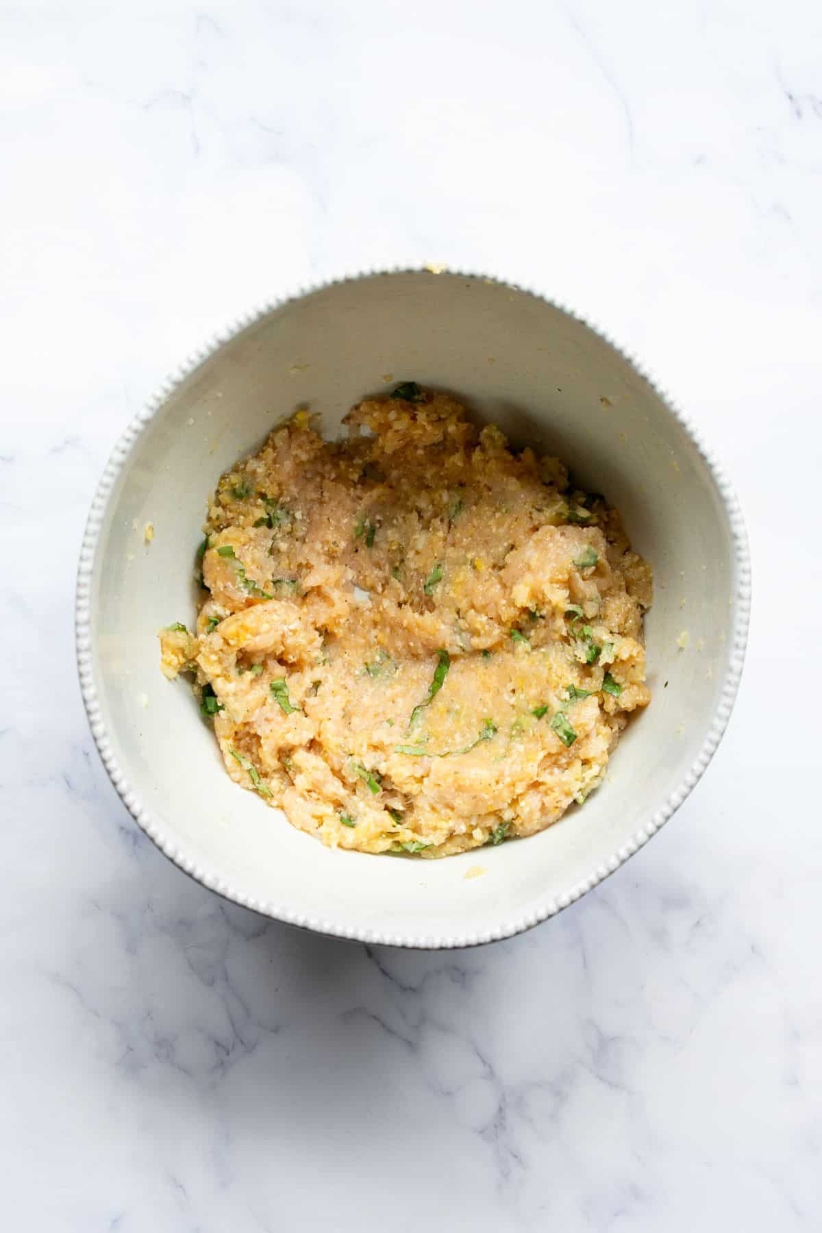 Ground chicken parmesan burger mixture in a bowl.