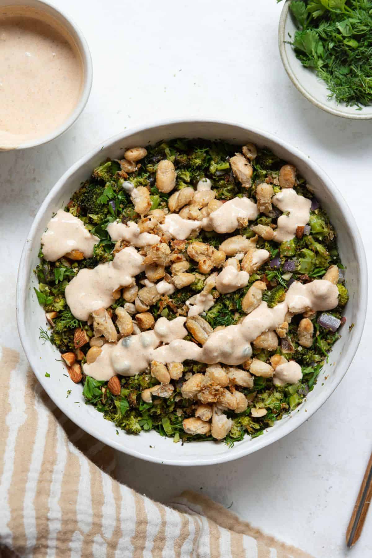 Roasted broccoli salad with crispy white beans and lemon yogurt dressing drizzled on top.