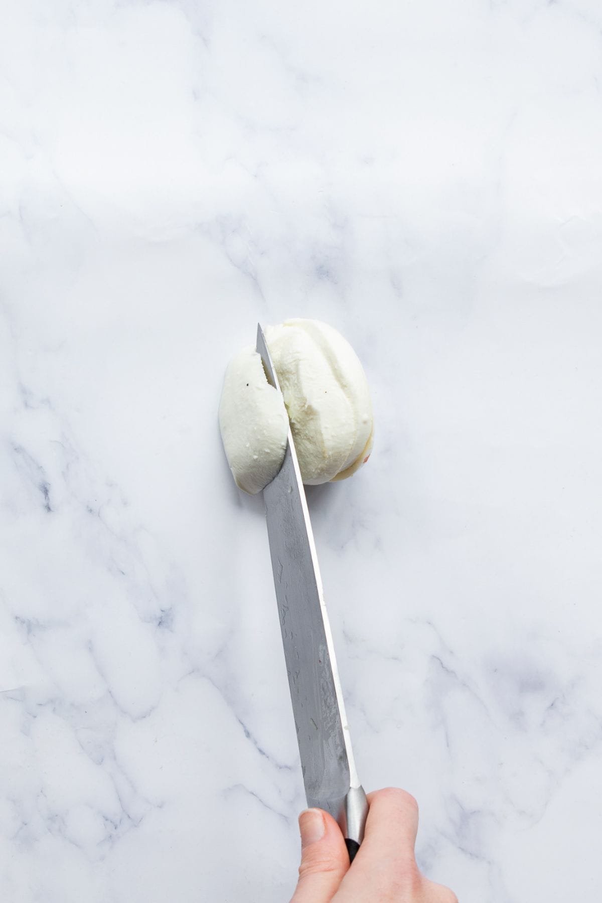 Slicing fresh mozzarella for stuffed chicken burgers.