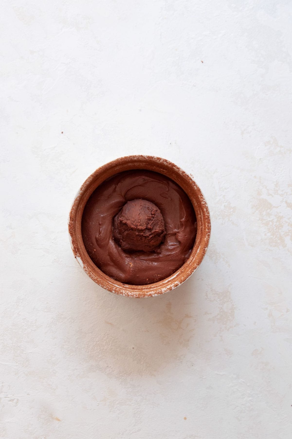 Frozen ganache ball on top of batter in a ramekin.
