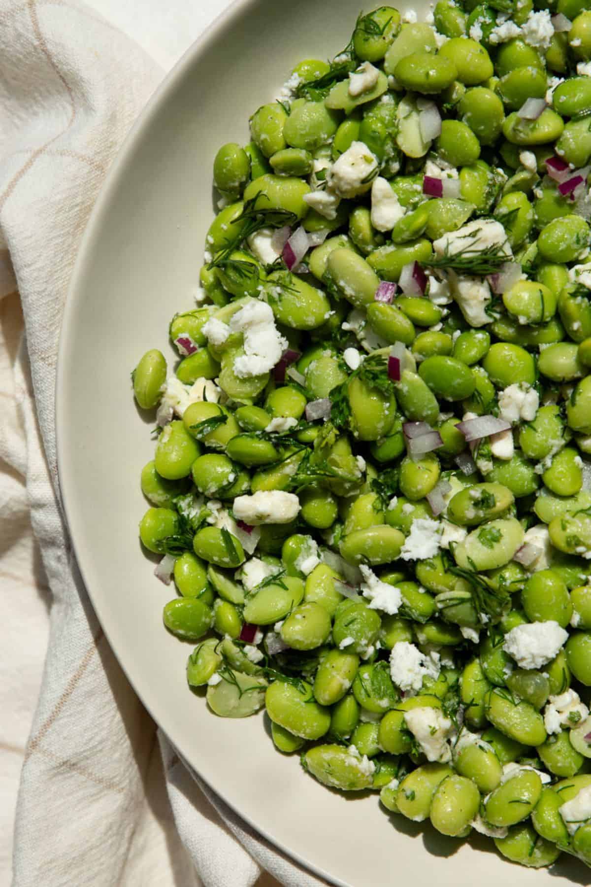 Close-up of high-protein edamame salad with crumbled feta and chopped dill.