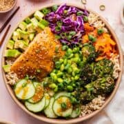 High-protein teriyaki salmon bowl with glazed salmon, avocado, edamame, crispy broccoli, and cucumber.