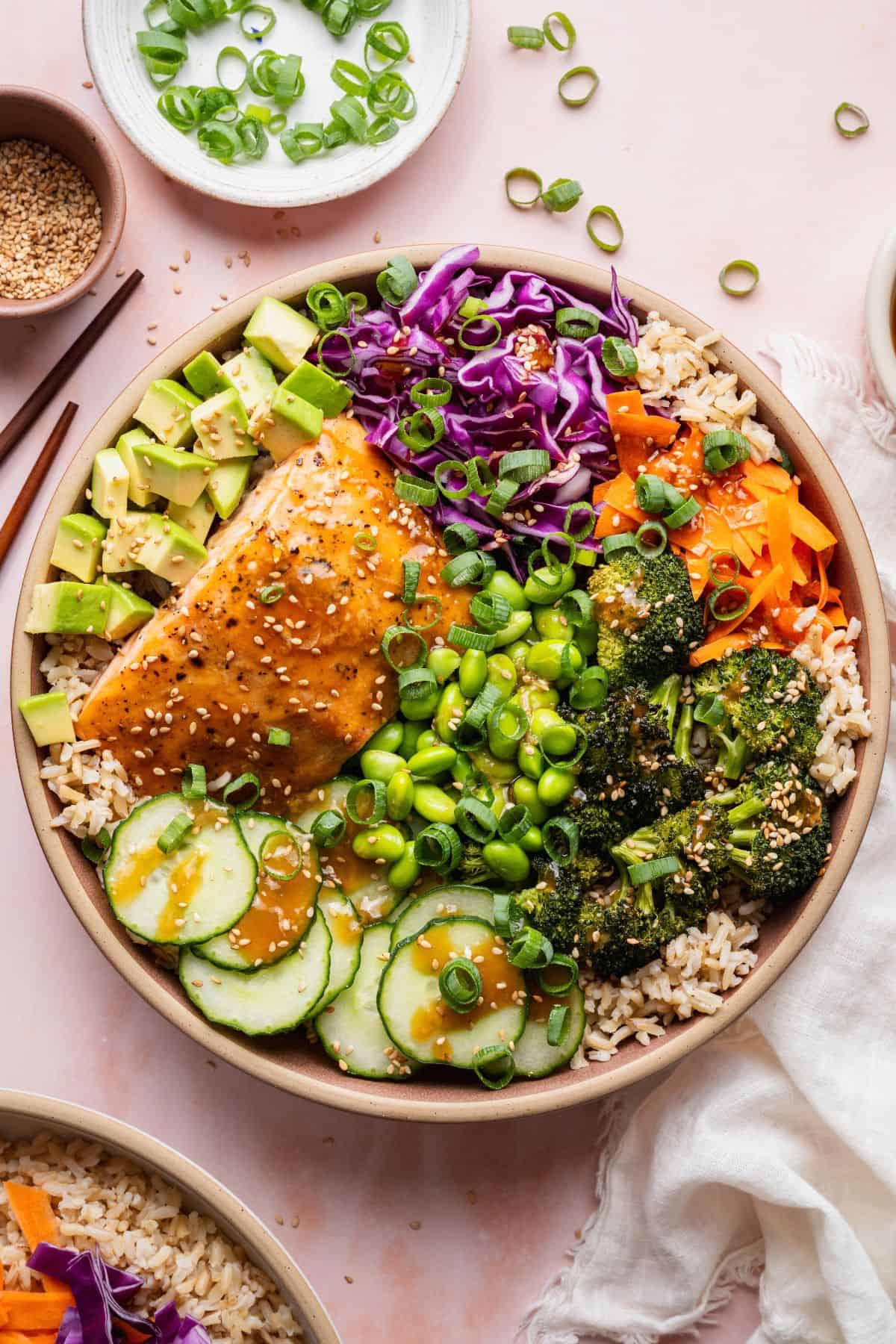 Overhead teriyaki salmon Buddha bowl topped with sesame seeds, green onions, and teriyaki sauce.