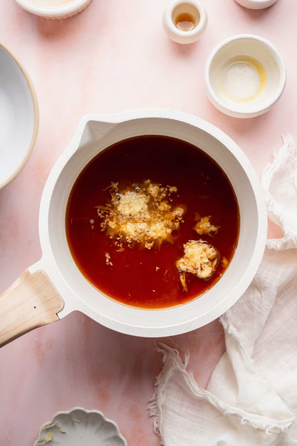 Soy sauce, orange juice, grated ginger, and garlic in a saucepan before simmering into teriyaki sauce.