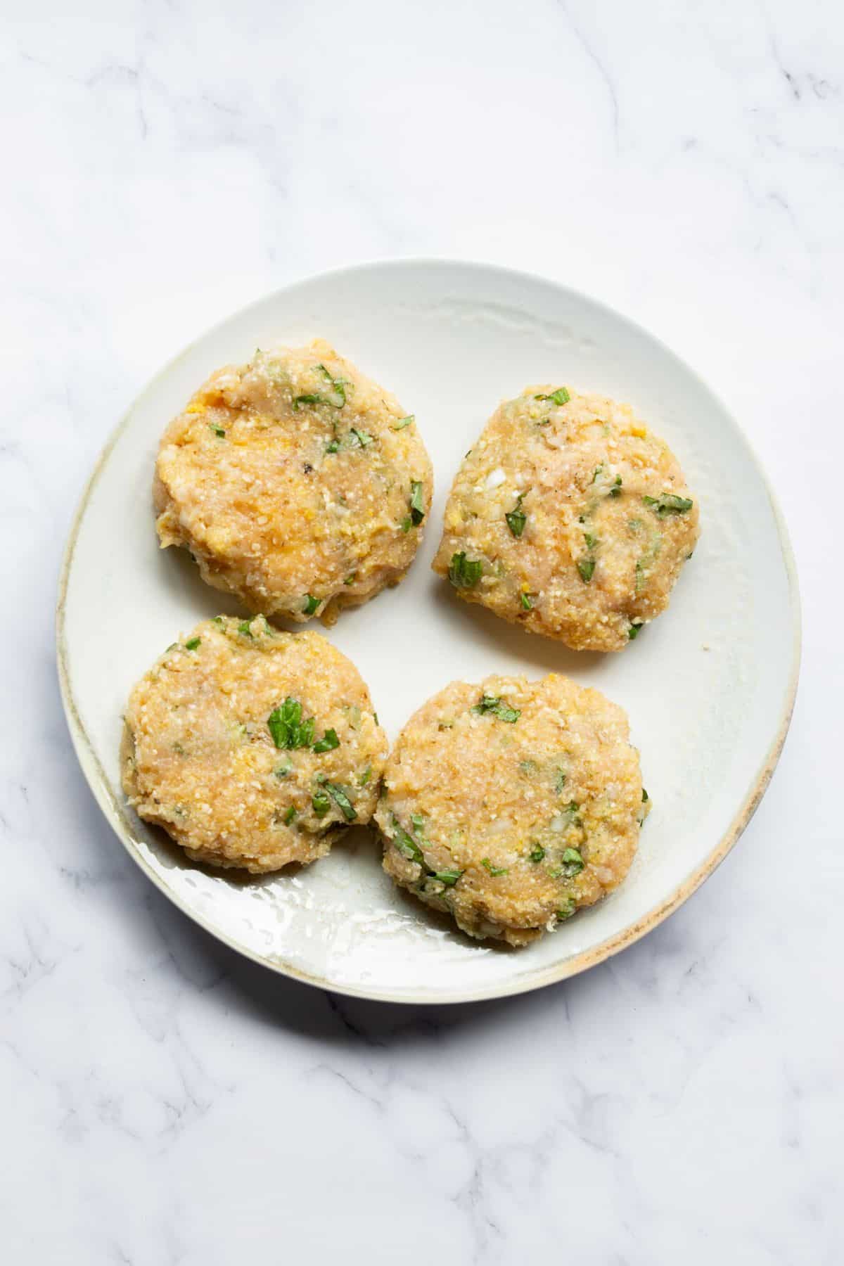 Four mozzarella stuffed chicken patties before cooking.