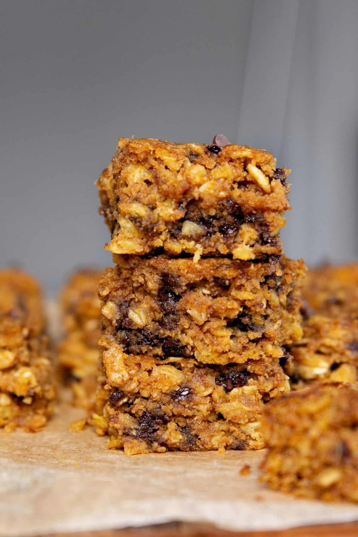 Stack of three pumpkin chocolate chip oatmeal bars showing rolled oats and melted chocolate inside.