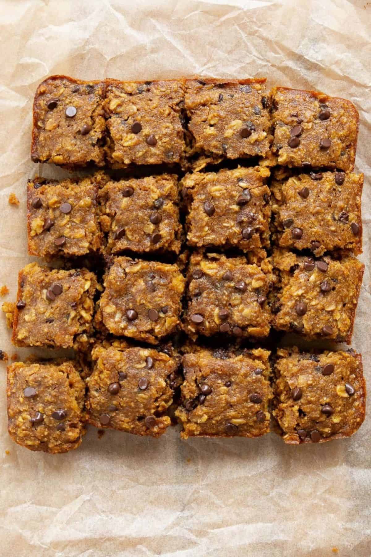 Pumpkin oatmeal bars with chocolate chips cut into squares on parchment paper.