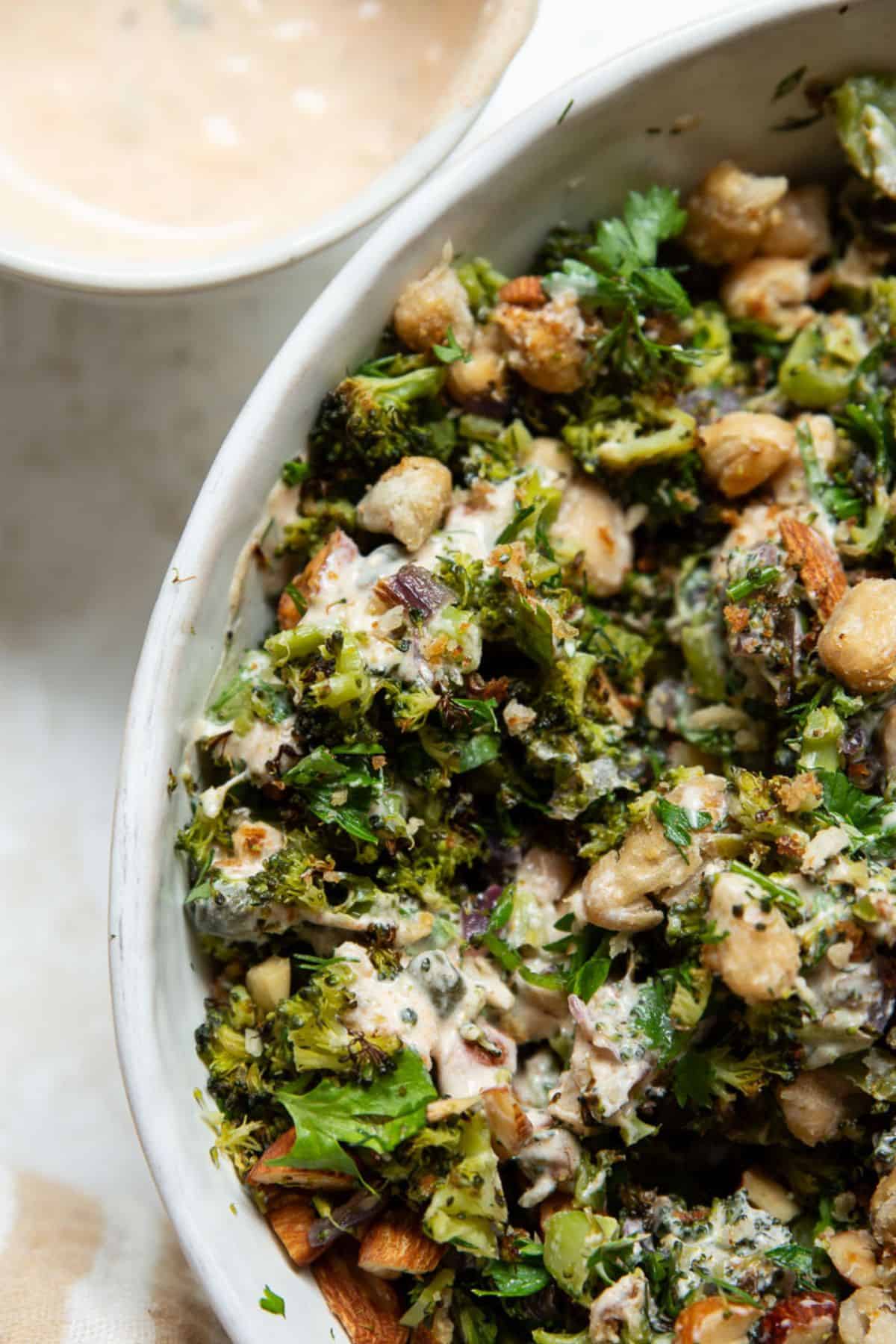 Close-up of roasted broccoli salad with crispy white beans, almonds, fresh herbs, and creamy lemon yogurt dressing.