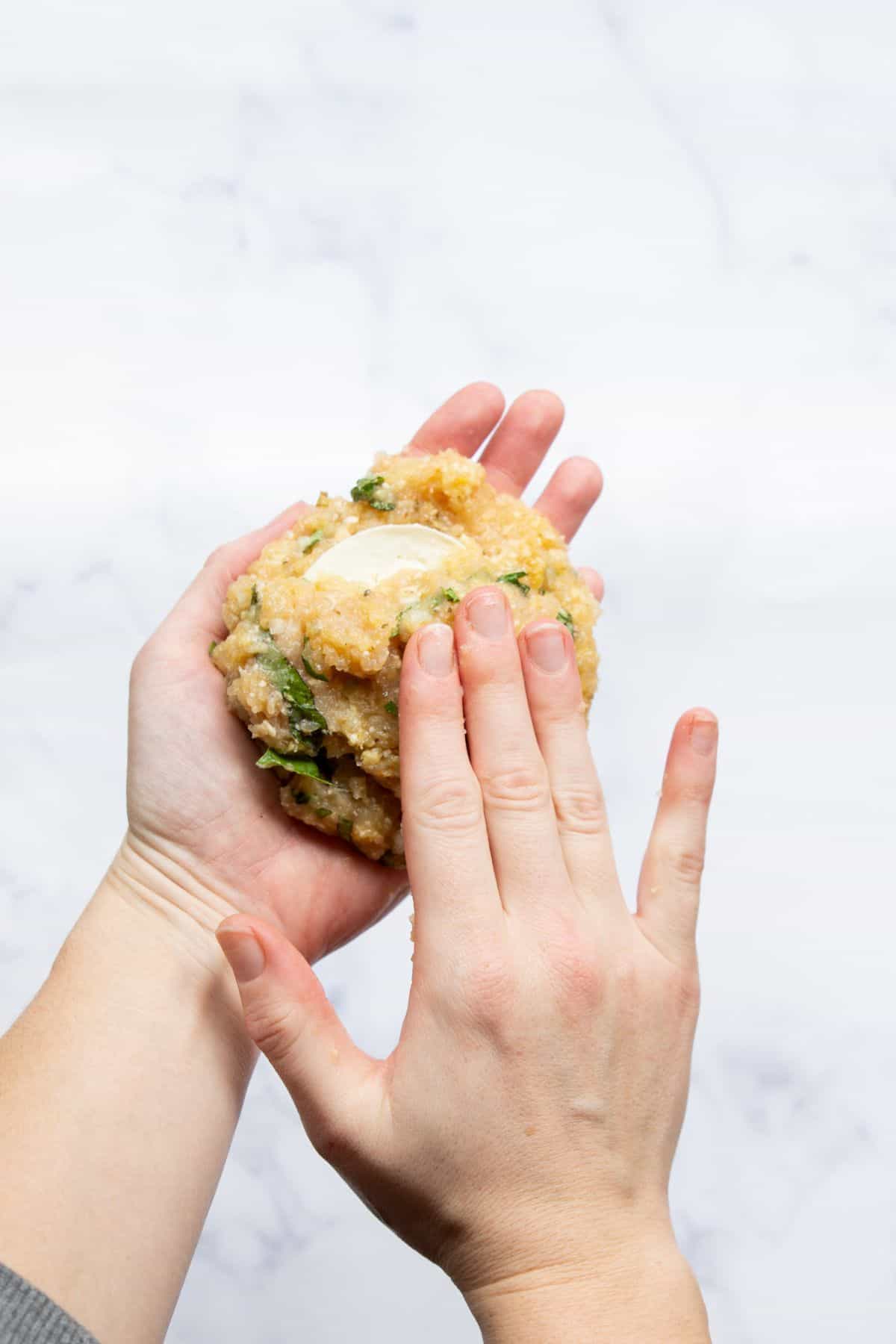 Sealing a slice of mozzarella inside a ground chicken patty.