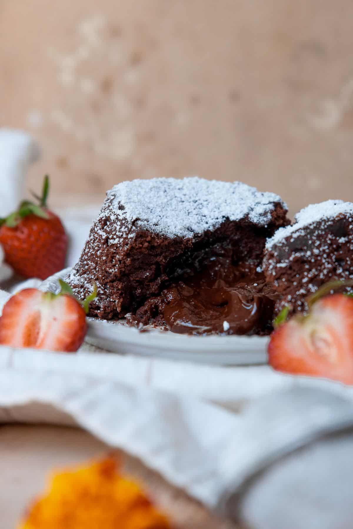 Vegan chocolate lava cake cut open with a gooey chocolate center.