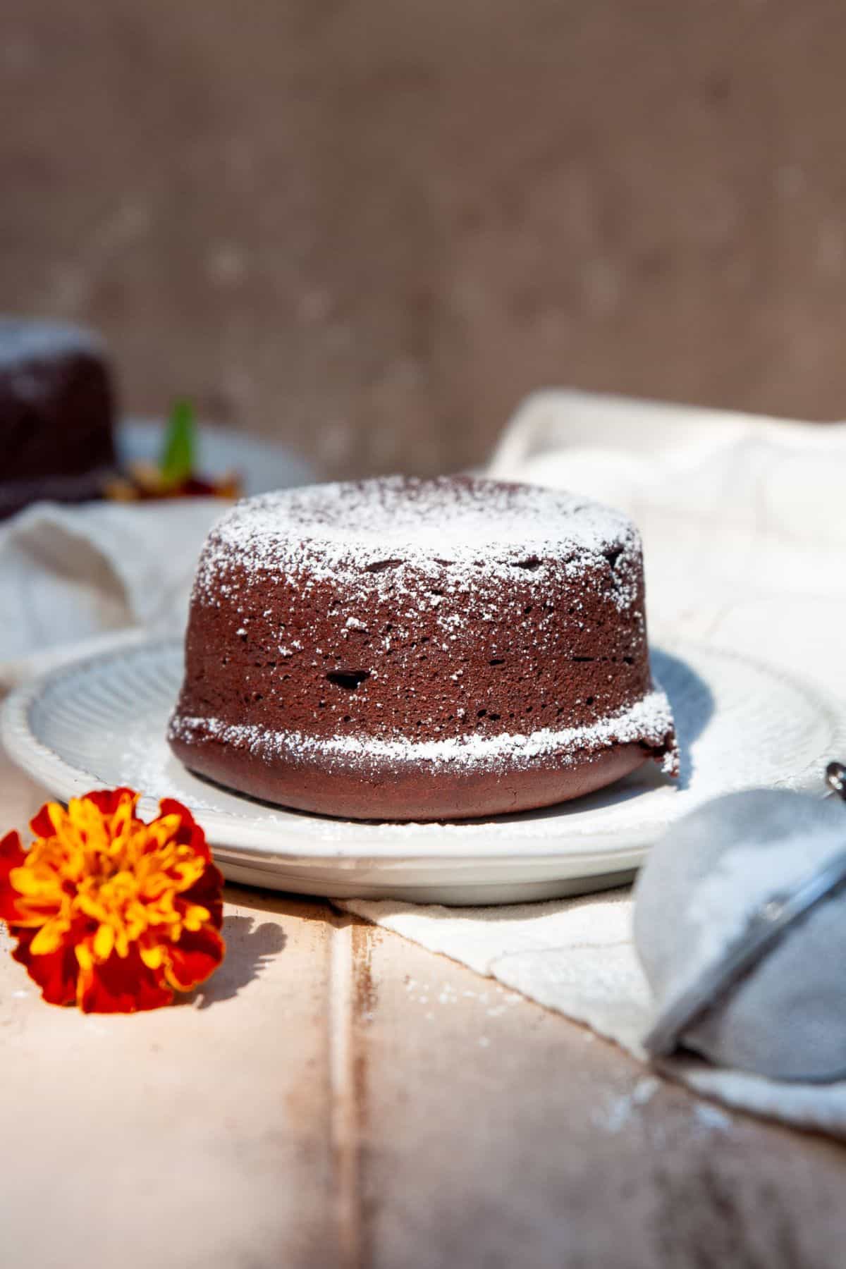 Vegan molten lava cake dusted with powdered sugar on a white plate.