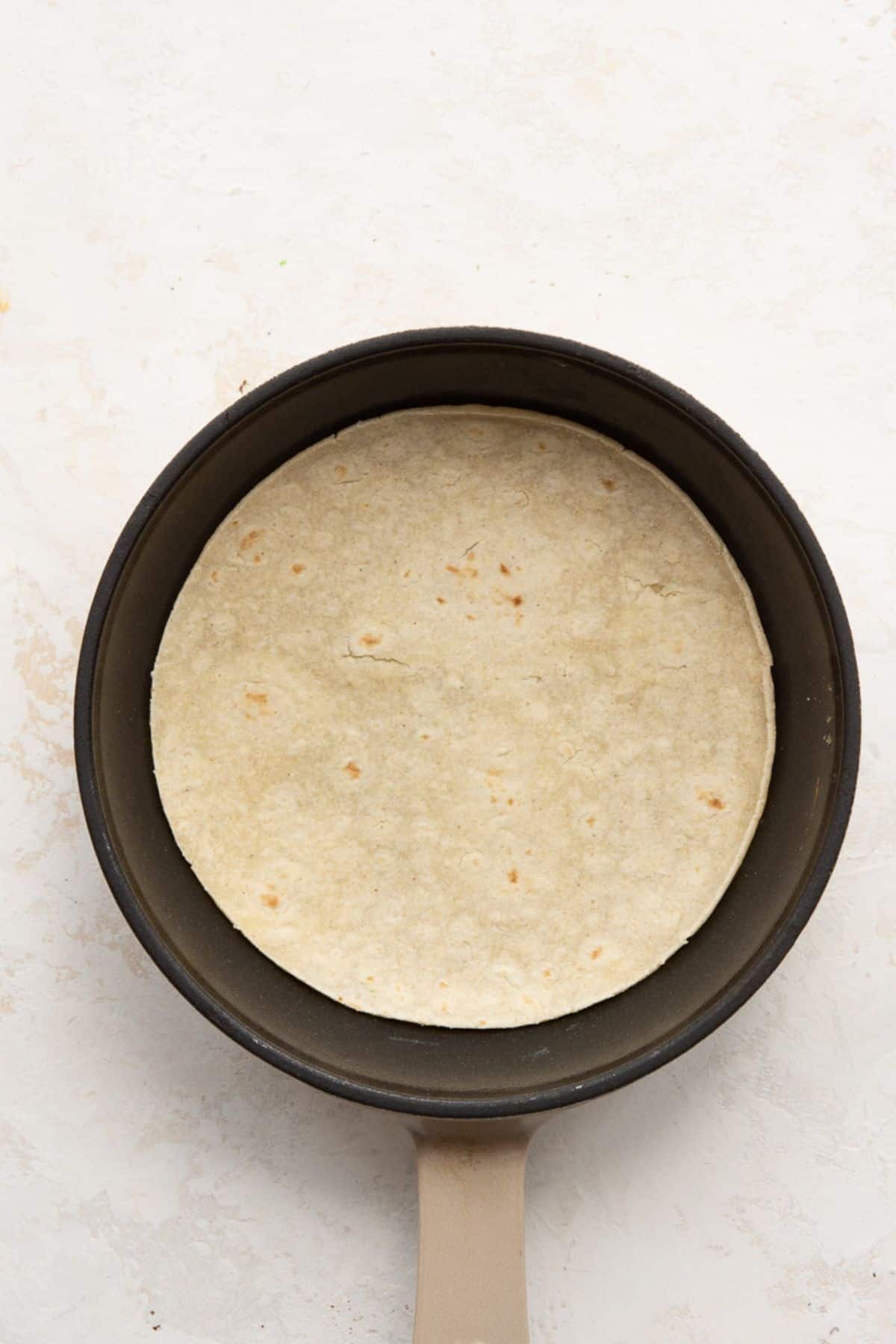 Corn tortilla warming in a dry skillet.