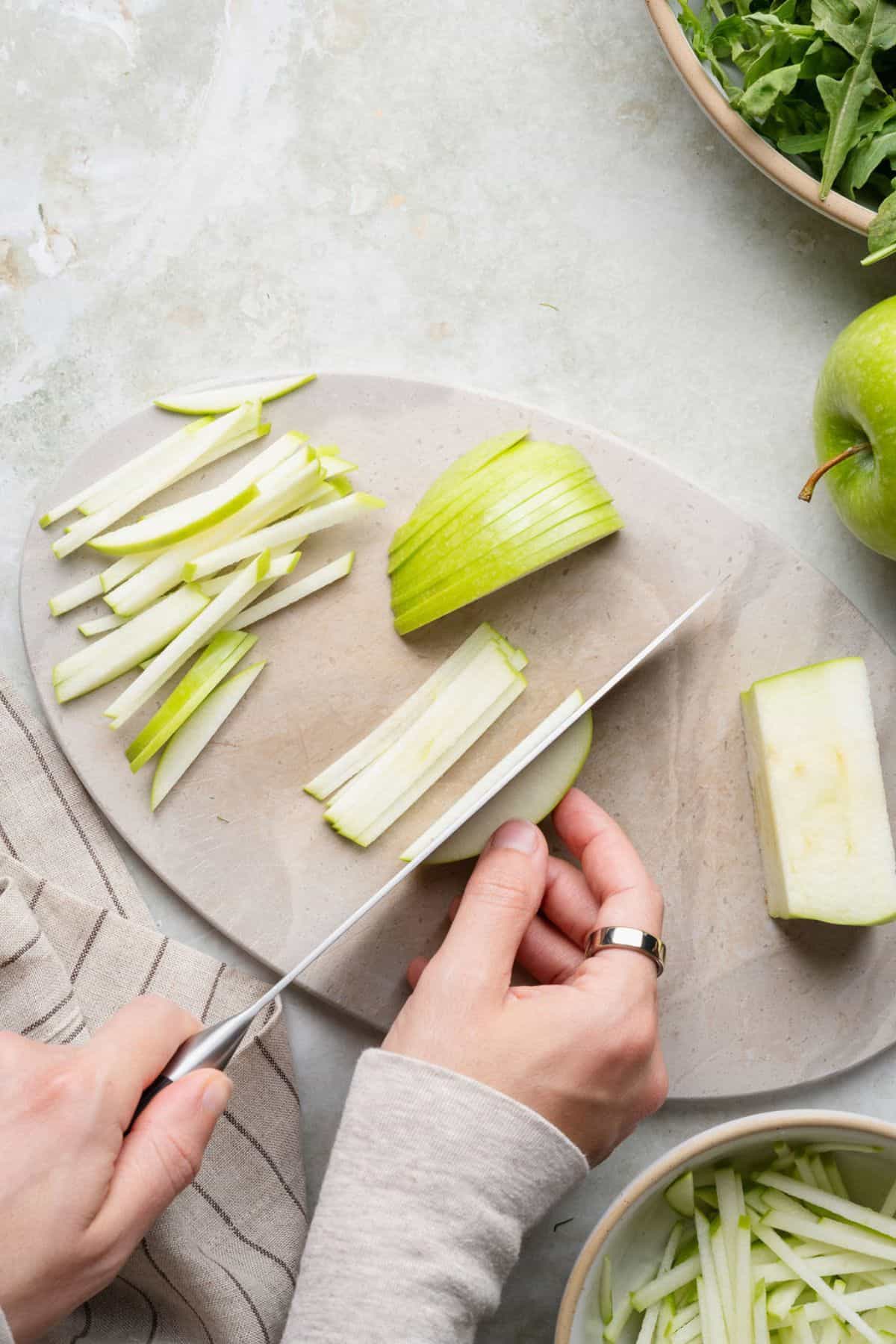 Cutting Granny Smith apple slices into thin matchsticks for fennel salad.