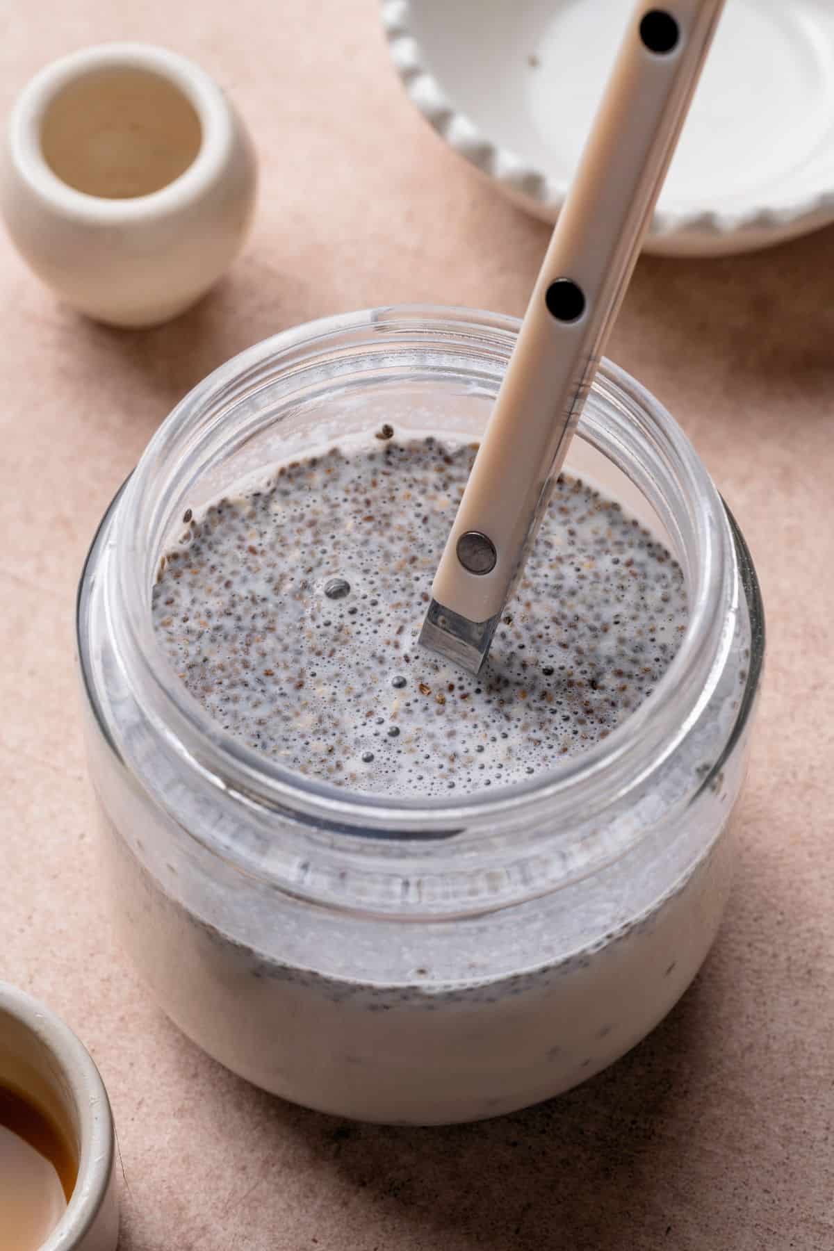 Chia seeds stirred into coconut milk mixture in a glass jar.