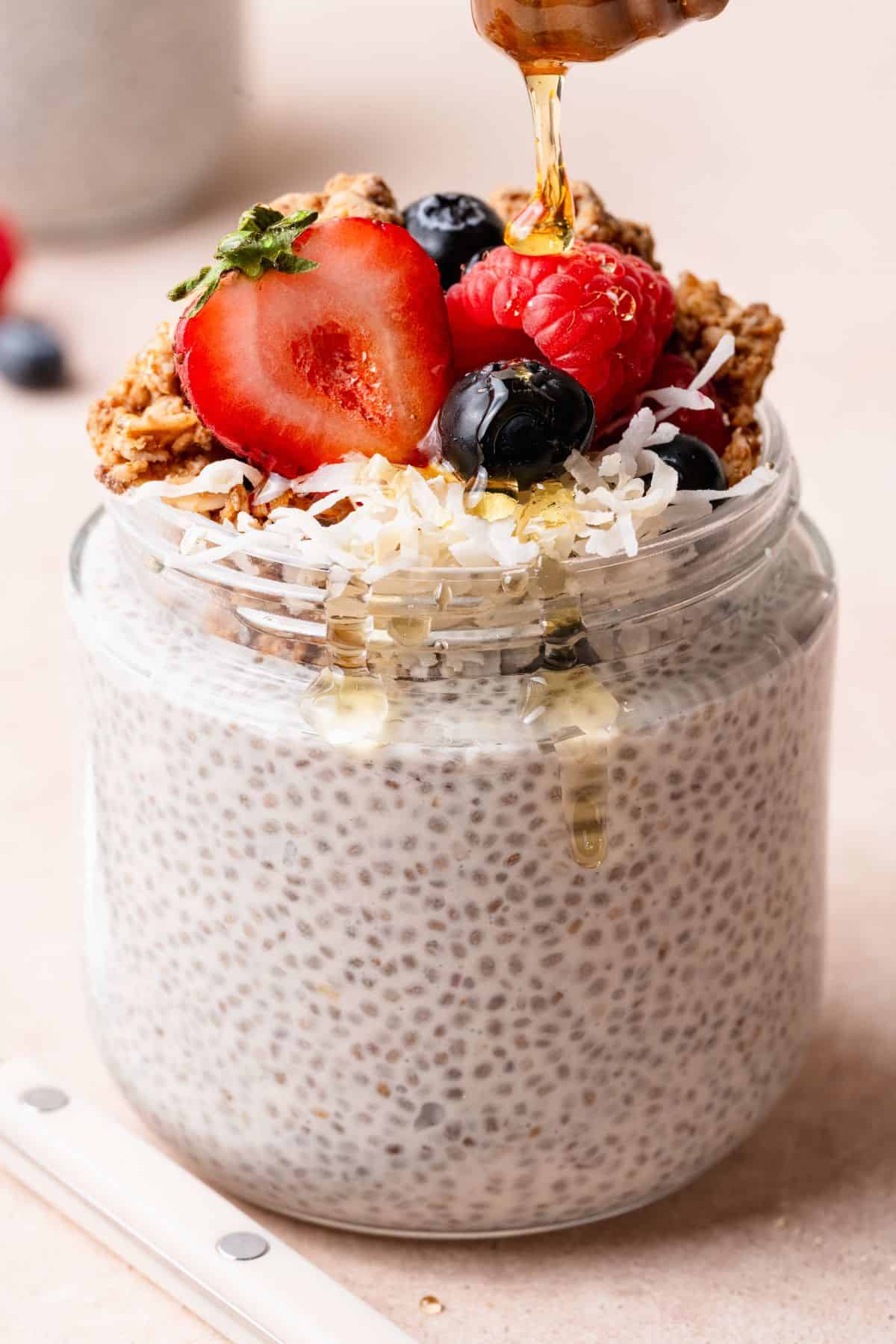 Honey drizzled over coconut chia pudding topped with berries, granola, and shredded coconut.