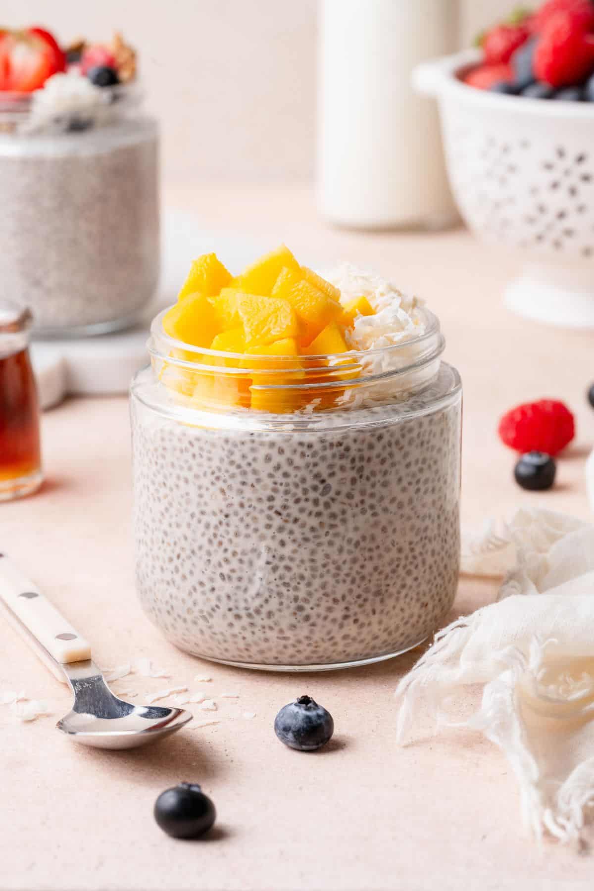 Coconut mango chia pudding in a glass jar topped with diced mango and shredded coconut.