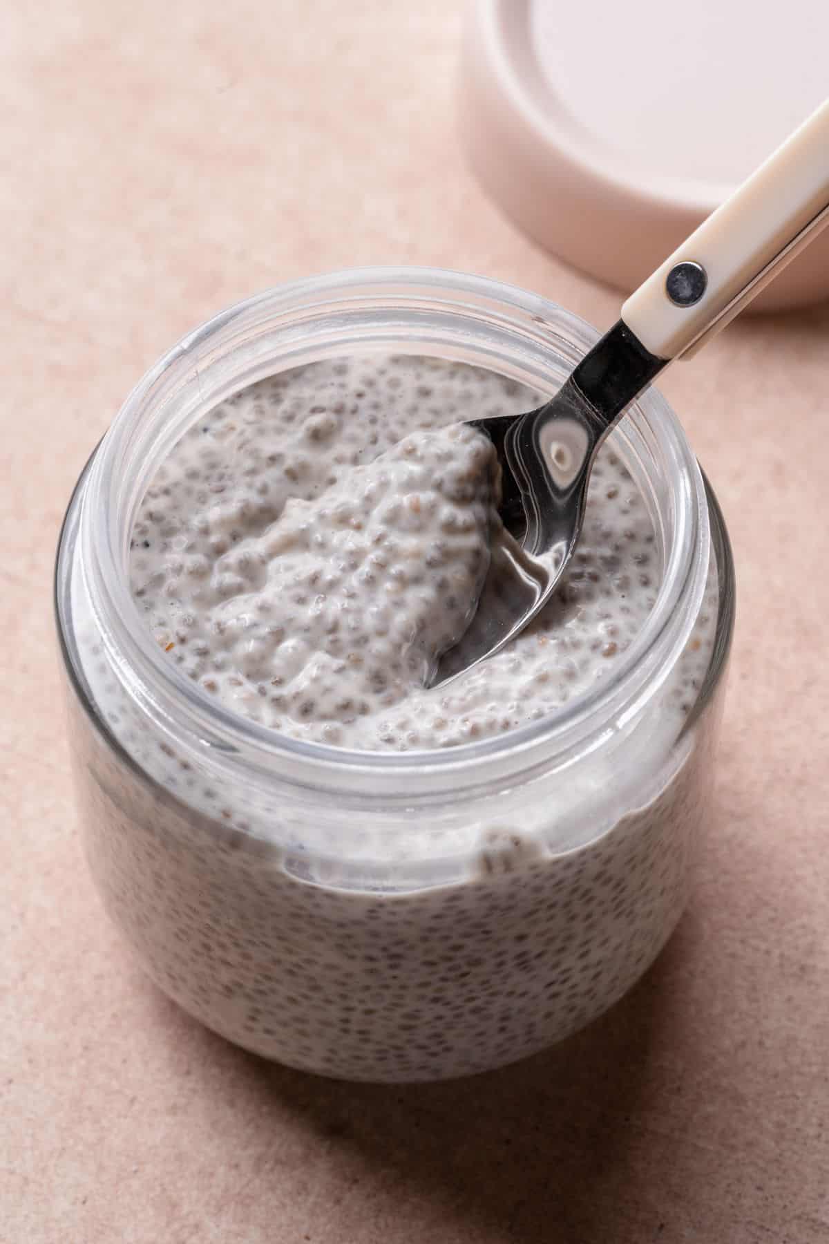 Spoon scooping thick, creamy coconut chia pudding from a glass jar.
